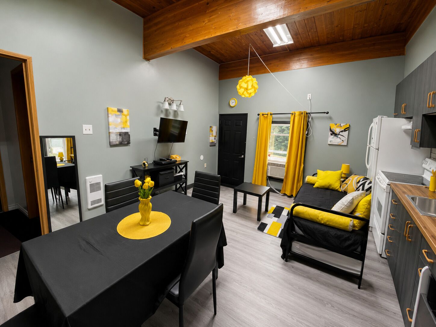 Un espace de vie compact comprenant un coin repas, un lit, une kitchenette et un téléviseur.