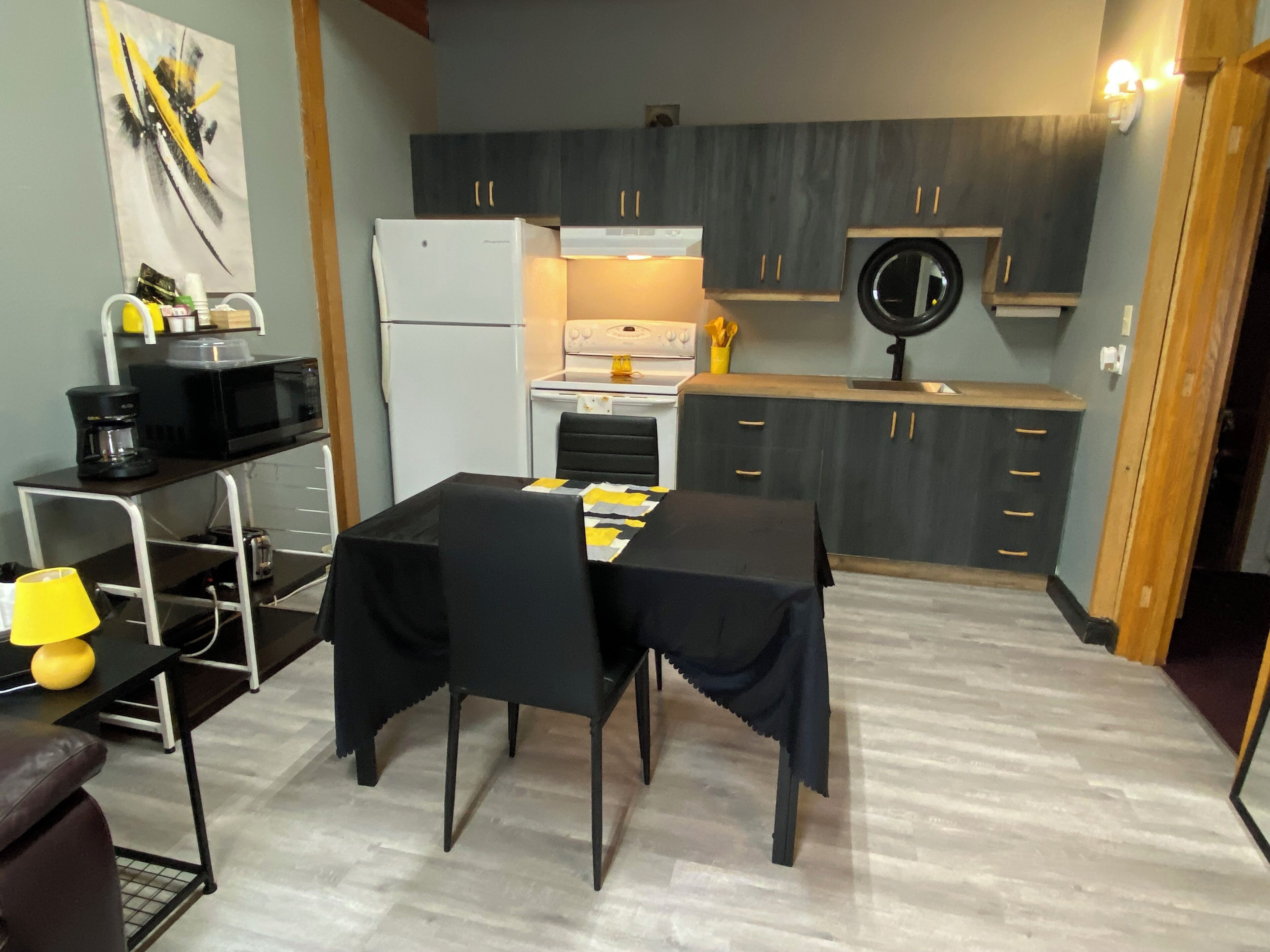 Eine kleine Küche mit Essbereich, ausgestattet mit Kühlschrank, Mikrowelle, Herd und Spüle.