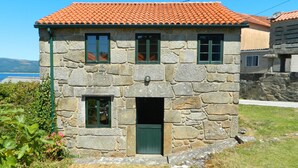 A stone house with a red-tiled roof, a green door, and a small window with a shutter. - Little house with seaviews (Pedrafigueira)