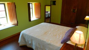 A bedroom with a bed, a nightstand, a lamp, a window, and a mirror. - Little house with seaviews (Pedrafigueira)