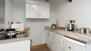 A modern kitchen with white cabinets, a built-in stove, and a countertop with a coffee maker and utensils.