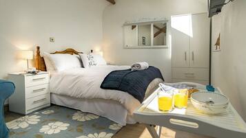 A bedroom with a bed, bedside table, and a breakfast tray with orange juice.
