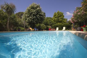 A swimming pool with clear blue water, surrounded by lush greenery and trees. - Secure, heated swimming pool; air-conditioned apartment in a villa 800 m from the sea (La Ciotat)