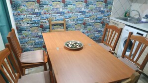 A dining area with a wooden table and chairs, a bowl of salad, and a wall covered with various license plates. - in the beating heart of Naples, Italy (Napoli)