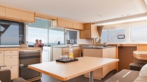 Una cocina moderna con armarios de madera, un refrigerador de acero inoxidable y un comedor con mesa y sillas.