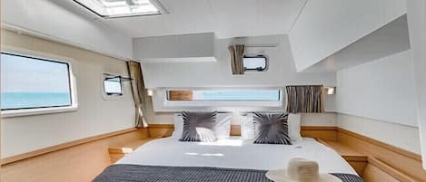 Ein modernes, helles Schlafzimmer mit einem großen Bett, einem Oberlicht und Meerblick.