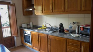 Una cocina con armarios de madera, horno empotrado, pileta y microondas.