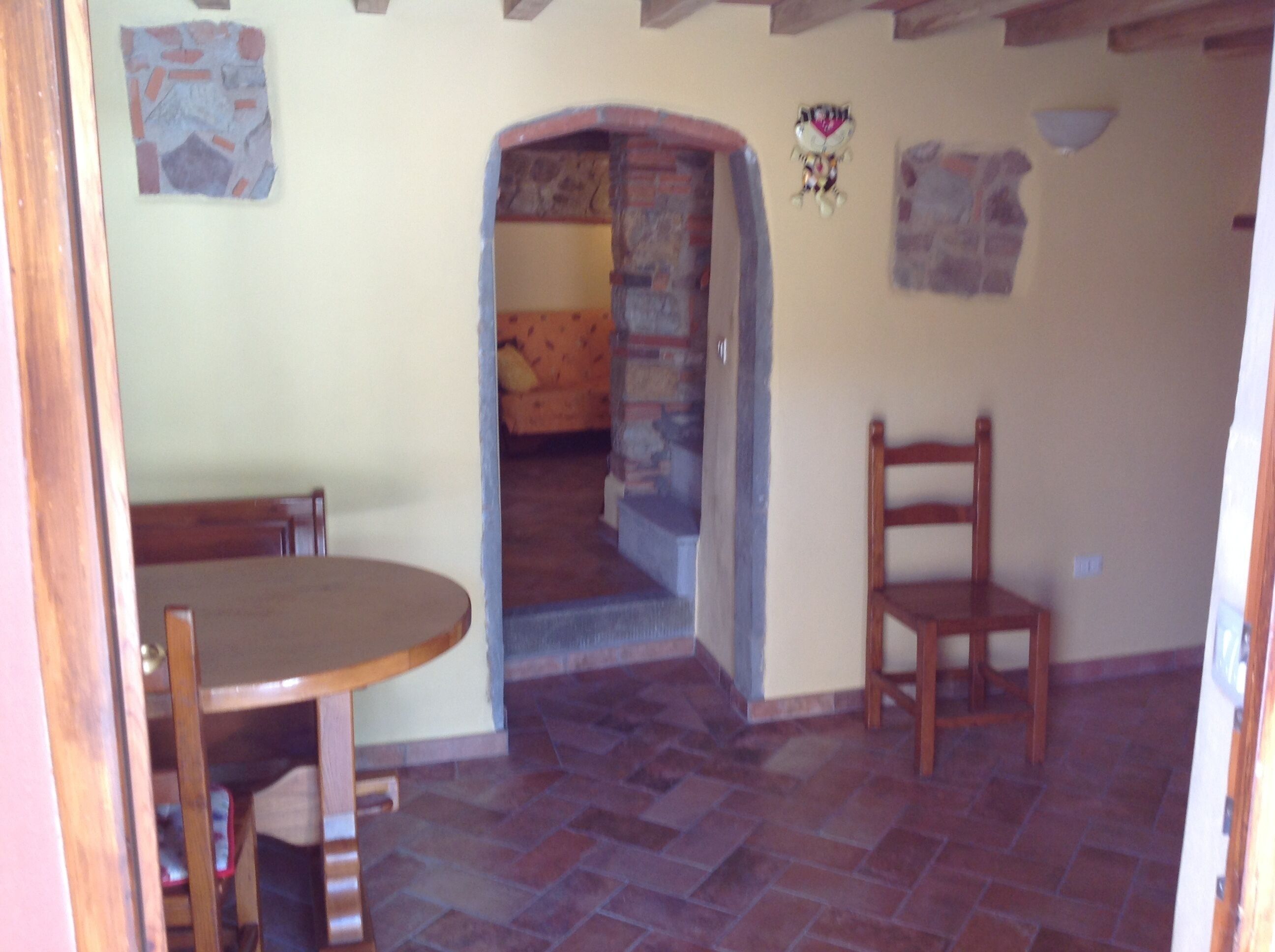 A room with a stone fireplace, a wooden table, and a chair.