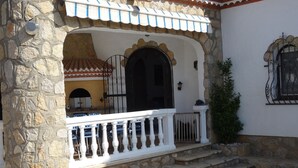 Un edificio in pietra con un balcone bianco, un tetto in tegole e un piccolo giardino.