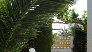 Una piccola area patio con erba sintetica, due poltrone bianche, un'amaca rossa e gialla e un vialetto in legno.