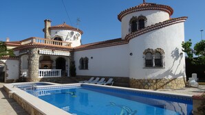 Vista di una piscina adiacente a un edificio con muri in pietra e tetto in tegole.