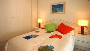 A bedroom with a bed, two bedside lamps, a nightstand, a wardrobe, and a framed picture on the wall. - BEACH APARTMENT 2rooms with PARKING (Tossa de Mar)
