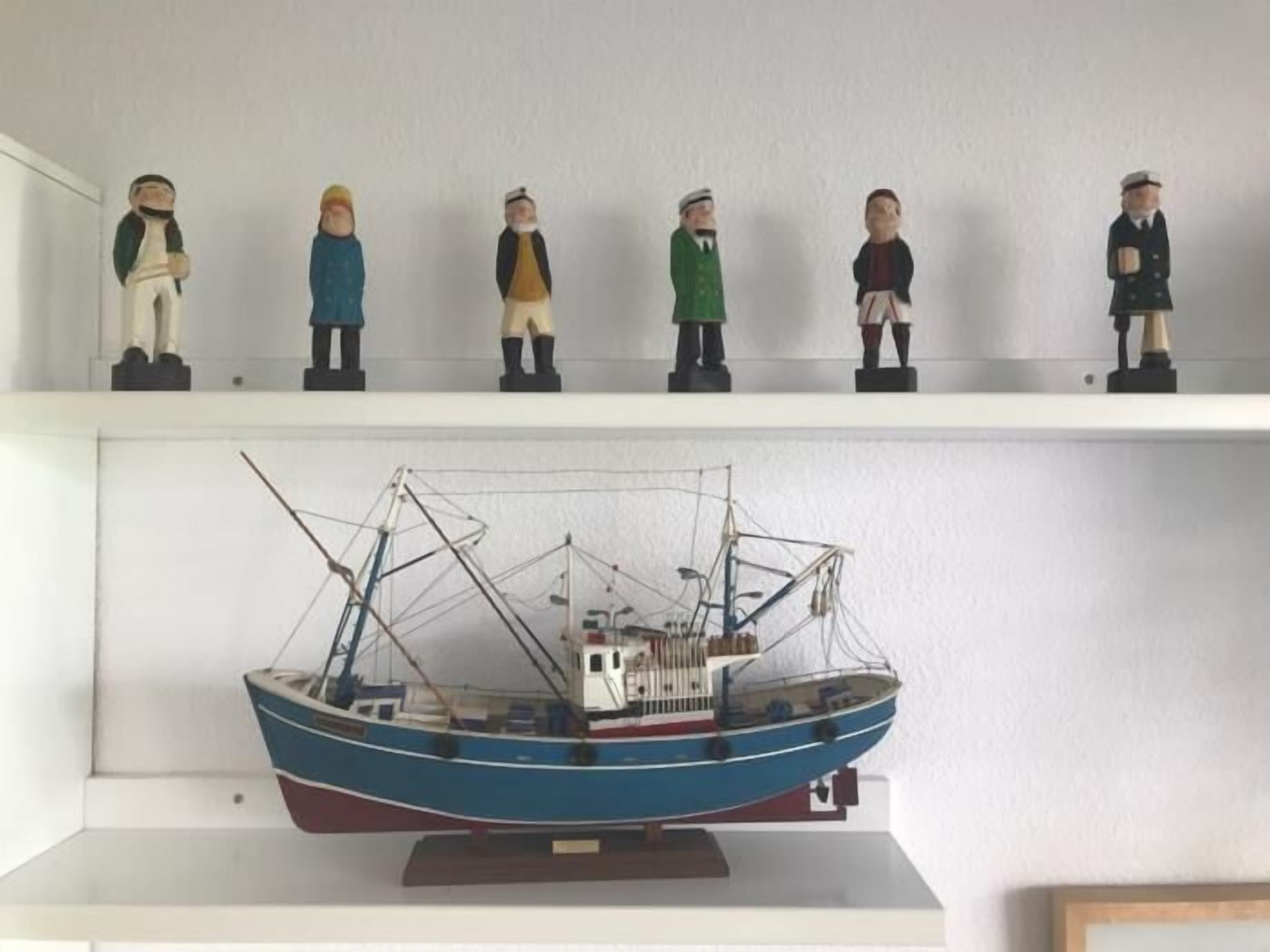 Un modelo de barco sobre una repisa con seis figuras encima.