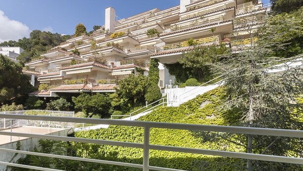 A multi-story building with balconies, surrounded by greenery and a clear sky. - BEACH APARTMENT 2rooms with PARKING (Tossa de Mar)