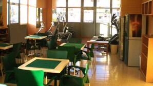 Une pièce équipée de matériel de sport, avec des chaises et des tables vertes.