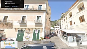A narrow street with buildings on either side, a small kiosk, and parked scooters. - Stylish Apartment - Minori (Minori)