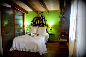 Relax in a traditional room with a large bed, nightstand, and table with candles.