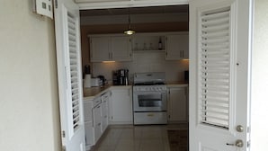 Una cucina compatta con pensili bianchi, un fornello e una macchina per il caffè.