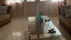 Un soggiorno con ventilatore a soffitto, tavolino in vetro e due divani con cuscini decorati.