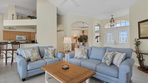 A spacious living room with two light blue sofas, a wooden coffee table, and a ceiling fan.