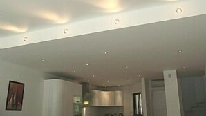Un intérieur moderne avec un éclairage encastré, un coin cuisine et un tableau encadré au mur.
