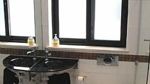 Une salle de bain avec des toilettes blanches, un lavabo noir et une fenêtre située au-dessus du lavabo.