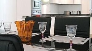 Un espace repas moderne avec une table noire, des sets de table blancs et des verres transparents.