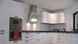 Une cuisine moderne avec des armoires blanches, un four encastré et une hotte de cuisson en acier inoxydable.