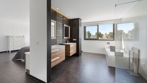 Un baño moderno con un ventanal grande, una bañera y un tocador con espejo.