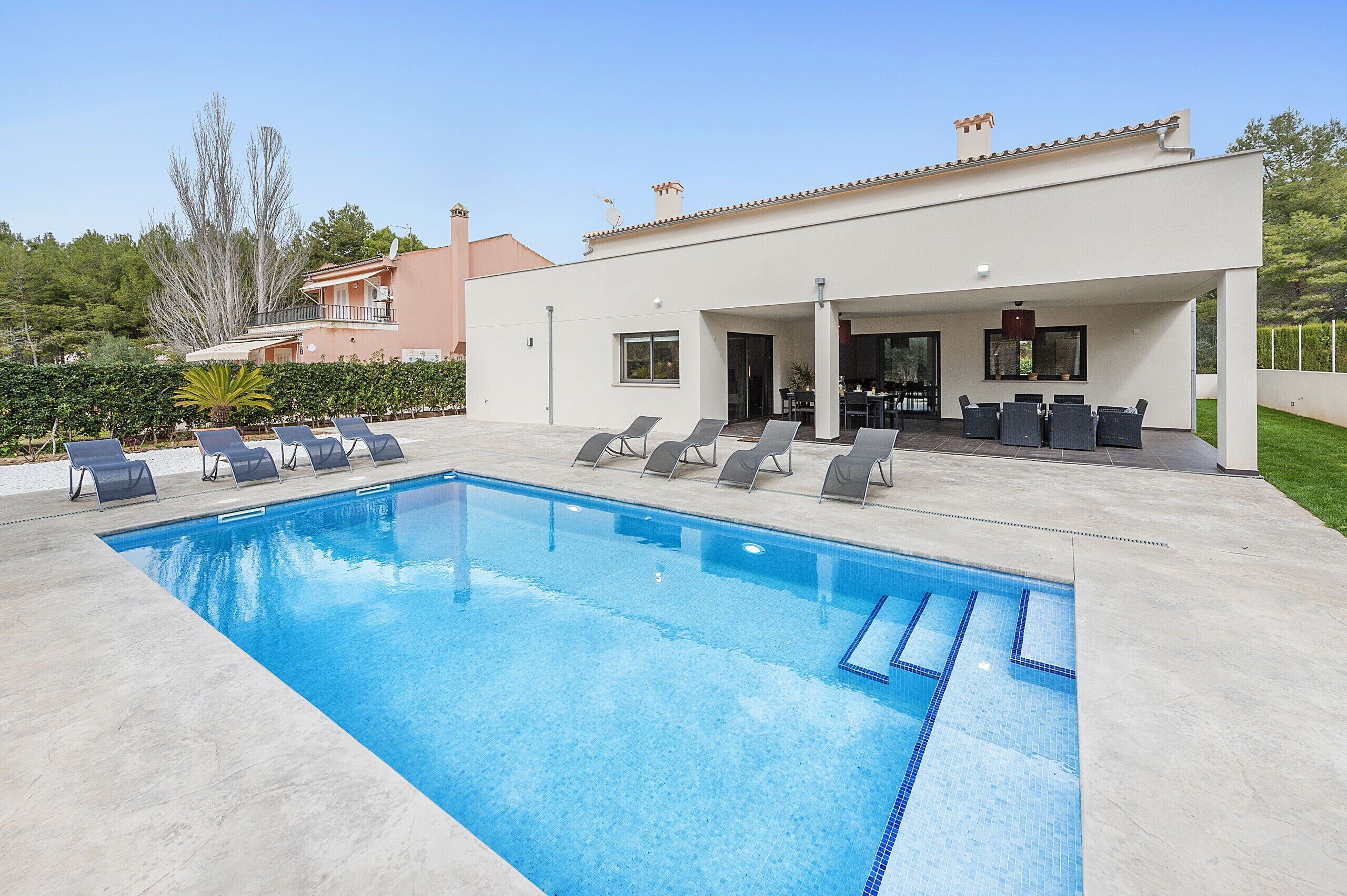 A modern outdoor pool area with lounge chairs and a covered seating area.