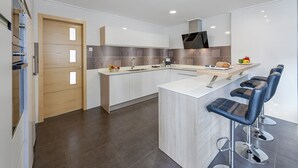 Una cocina moderna con una isla central, taburetes de bar y un televisor de pantalla plana.