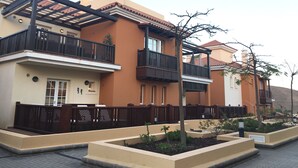 A residential building with balconies, a tiled roof, and a garden area. - Monte Carrera The Little Mermaid (Arguineguin)