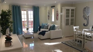 A modern living room with a white sofa, a dining table, and a chandelier. - Monte Carrera The Little Mermaid (Arguineguin)