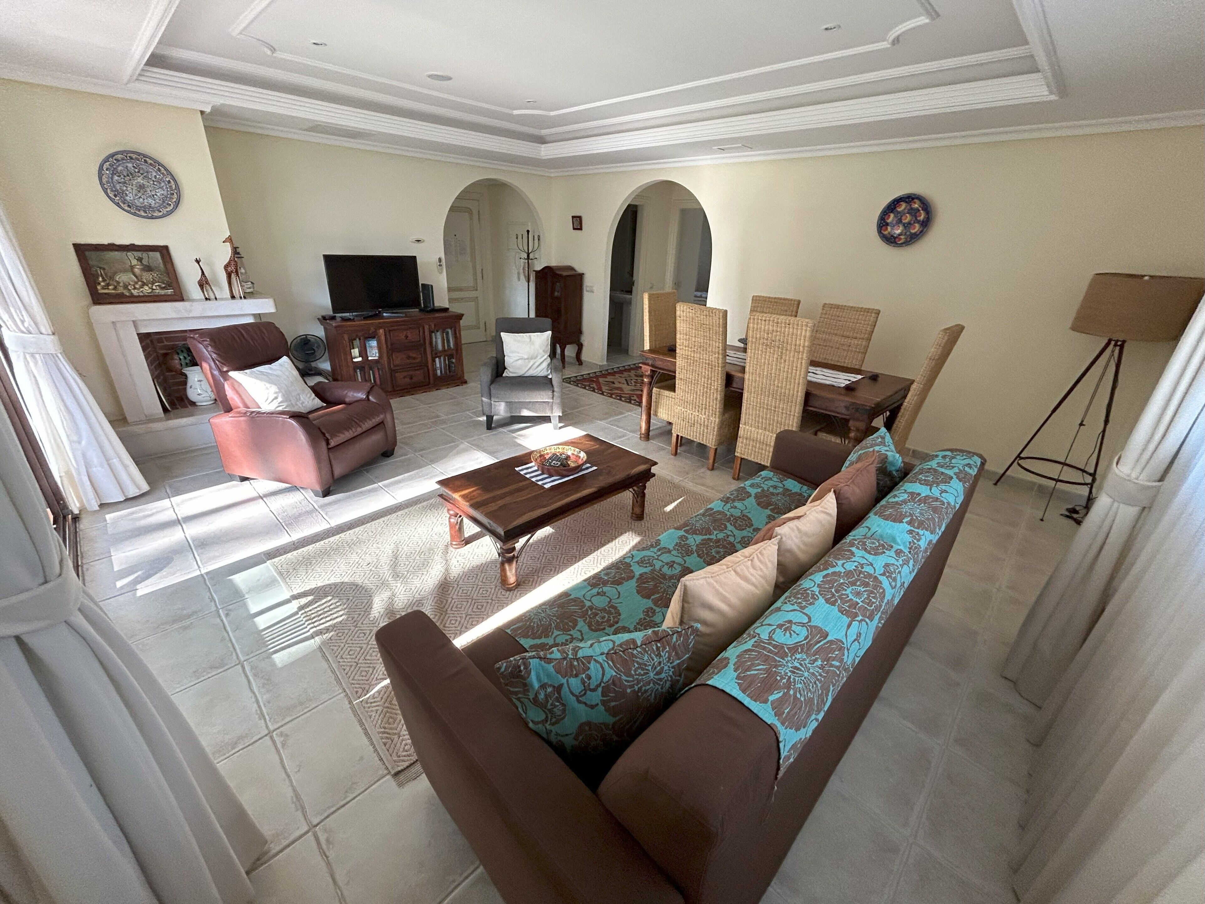 A spacious living room with a sofa, armchairs, a coffee table, and a dining area with chairs and a table.