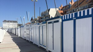 Une rangée de cabanes de plage blanches et bleues, avec un ciel dégagé en arrière-plan.