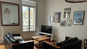 Un salon avec un canapé, une table basse, un téléviseur et des tableaux encadrés accrochés au mur.