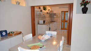 Comedor con una mesa preparada para cuatro, microondas y un lavamanos en la cocina contigua.