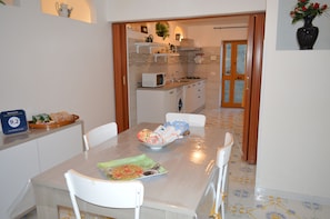 A dining area with a table set for four, a microwave, and a sink in the adjacent kitchen.