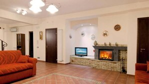 Ein Wohnzimmer mit Kamin, Fernseher und einer Couch.