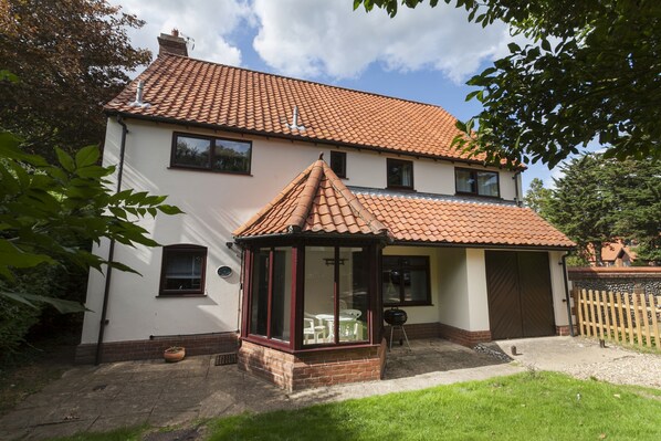 A two-story house with a tiled roof, a covered porch, and a garage.