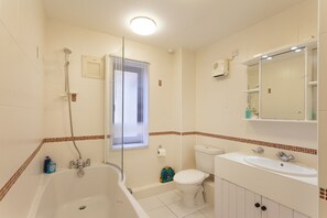 A bathroom with a bathtub, toilet, and sink. - Burnham A -  a self catering cottage that sleeps 3 guests  in 1 bedroom (Holt)