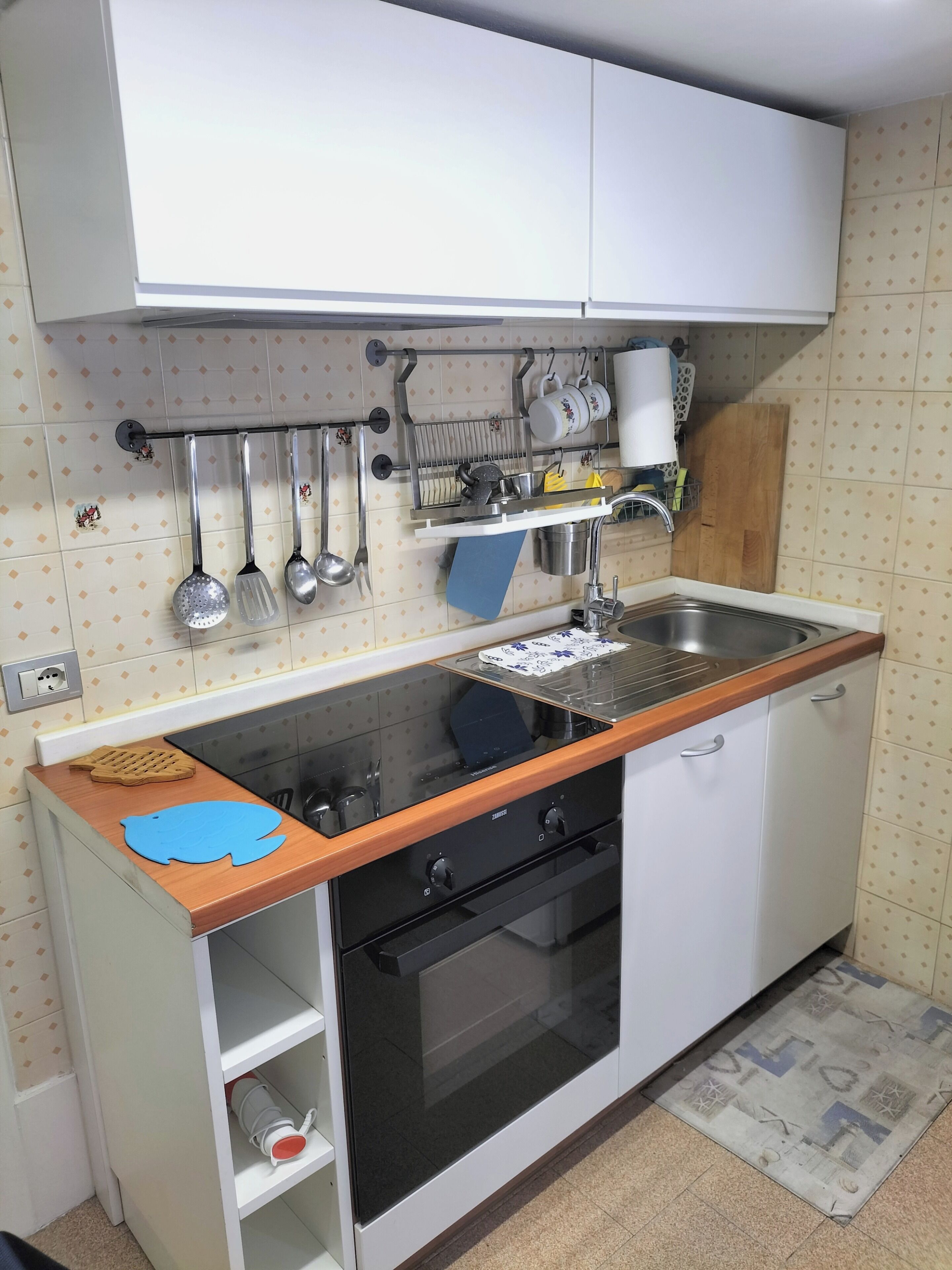A compact kitchen with white cabinets, a black oven, and a stainless steel sink.