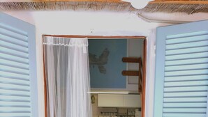 A doorway with a white curtain, leading to a kitchen area with a tiled floor and a bench with a polka dot cushion. - Charming and cozy little house in the center of Pomonte, just steps from the sea (Pomonte)