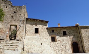 A stone building with a rustic appearance, featuring a small door and a window. - XIII century Castle overlooking an uncontaminated valley. (Gualdo Cattaneo)