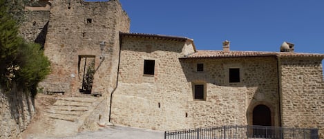 A stone building with a rustic appearance, featuring a small door and windows, and a paved pathway leading to it.