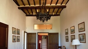 A hallway with wooden doors, a chandelier, and framed pictures on the walls. - XIII century Castle overlooking an uncontaminated valley. (Gualdo Cattaneo)