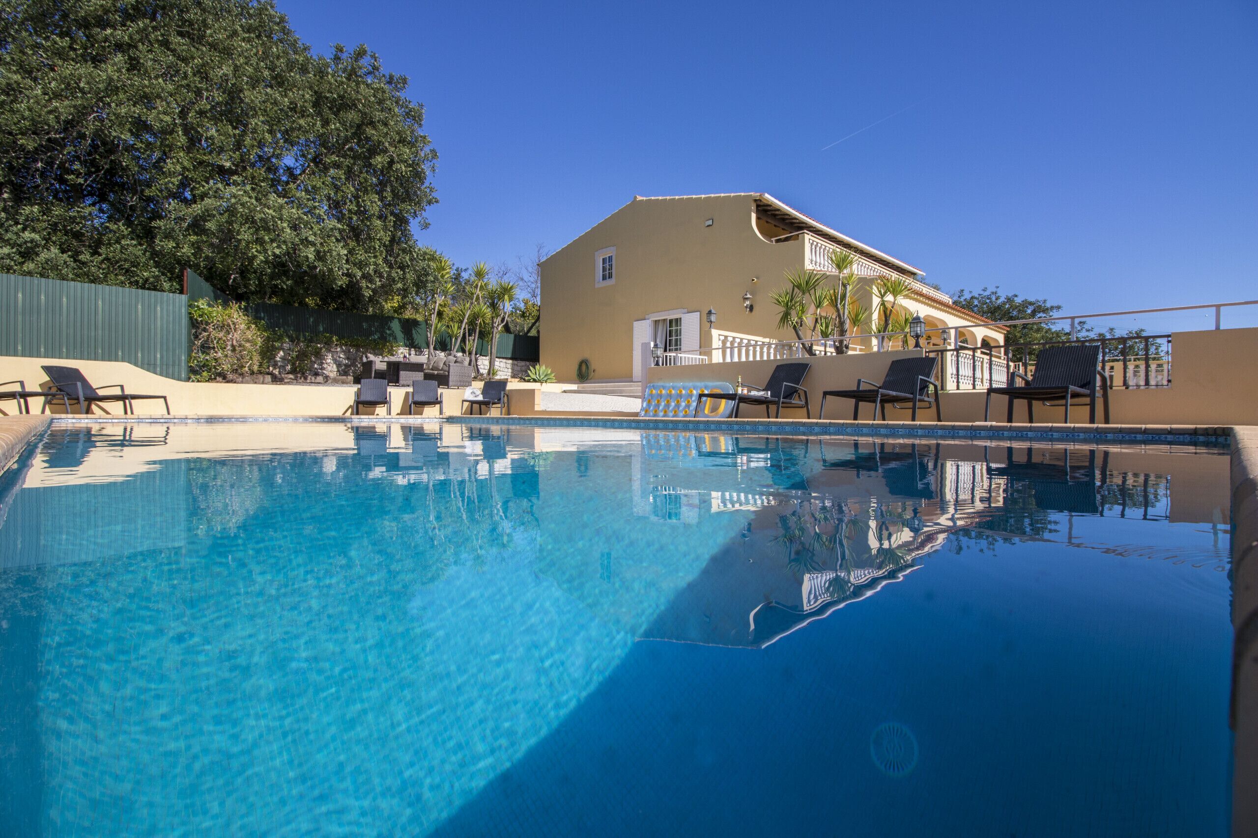 A swimming pool with lounge chairs and a building in the background.