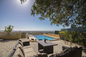 A rooftop pool with lounge chairs, a table with a bottle, and a view of the cityscape.