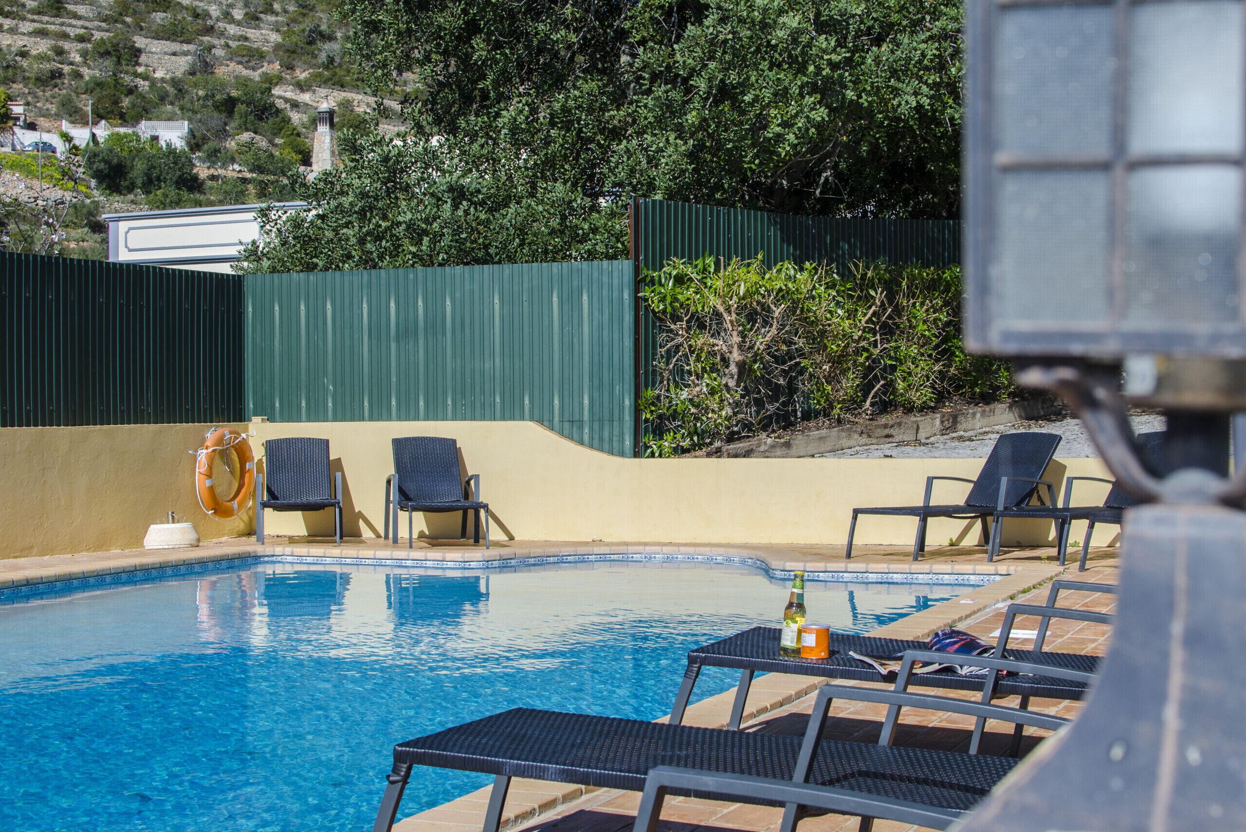 Una piscina con sillones de descanso, un flotador salvavidas y una botella de champán.