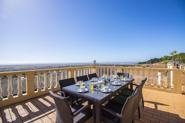 A terrace with a table set for dining, overlooking a scenic view.